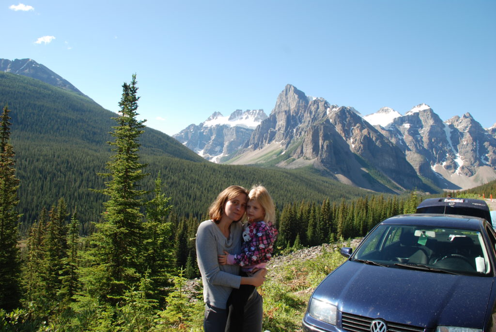 a woman and child posing for a picture in front of a car