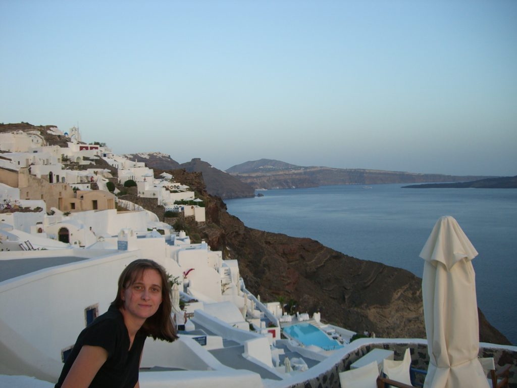a woman posing for a picture with a body of water in the background