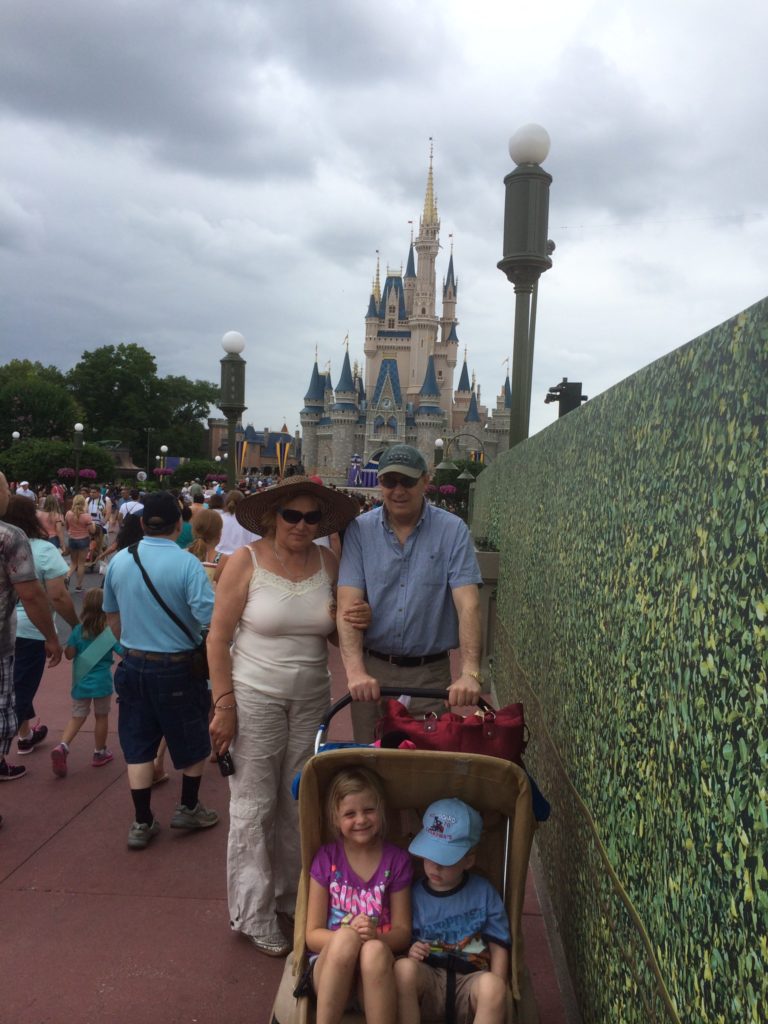 a man and woman with a stroller and a couple of children in front of a castle