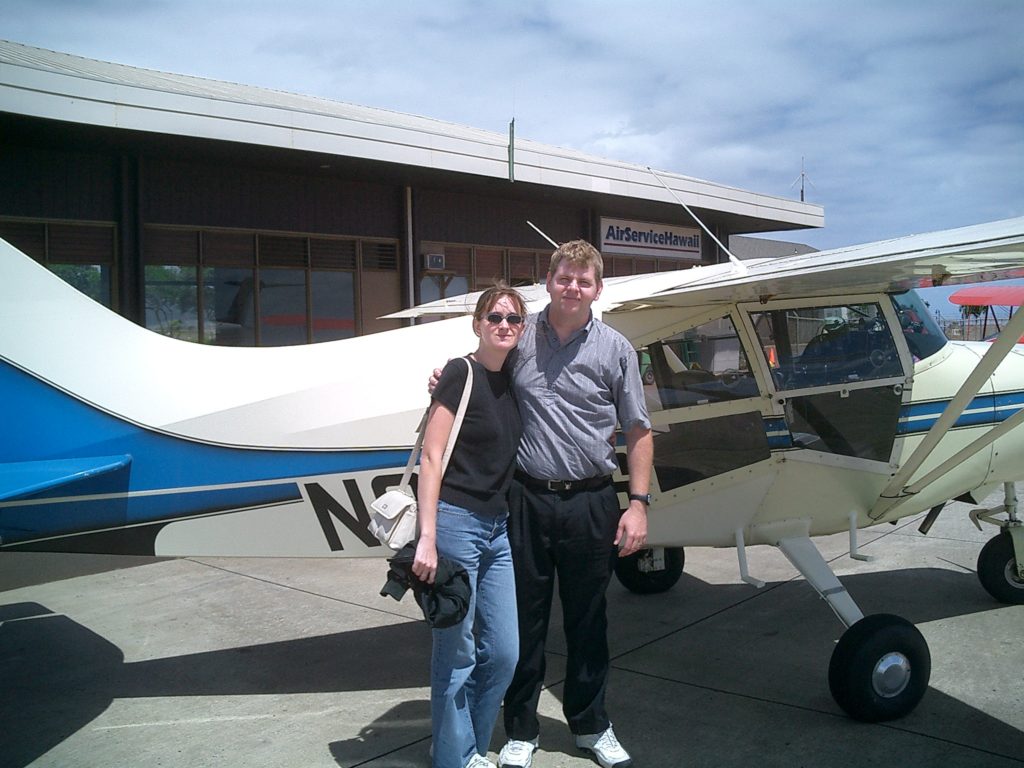 a man and woman standing in front of a small plane
