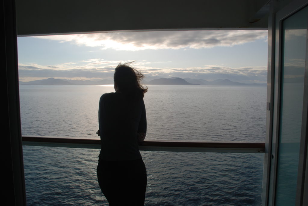 a woman looking out a window at the ocean