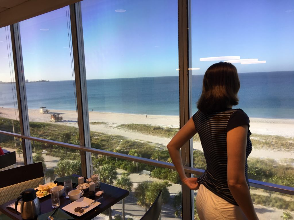 a woman looking out a window at the beach