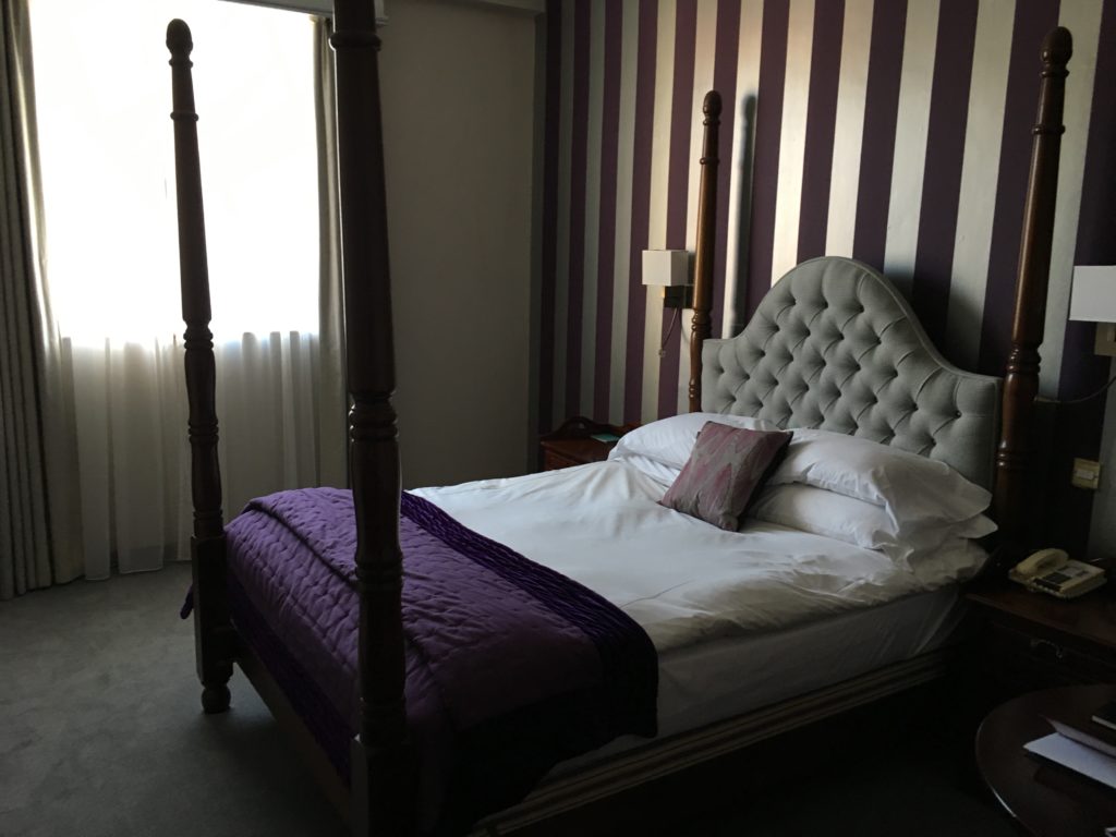 a bed with purple blanket and pillows