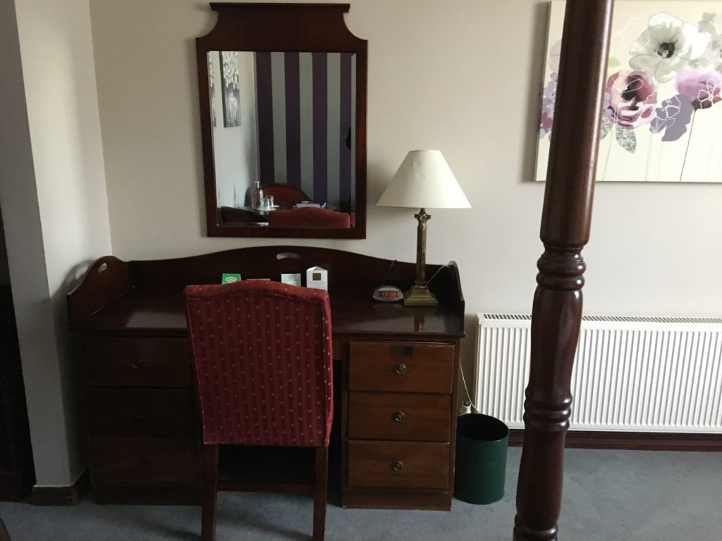 a desk with a lamp and mirror in a room