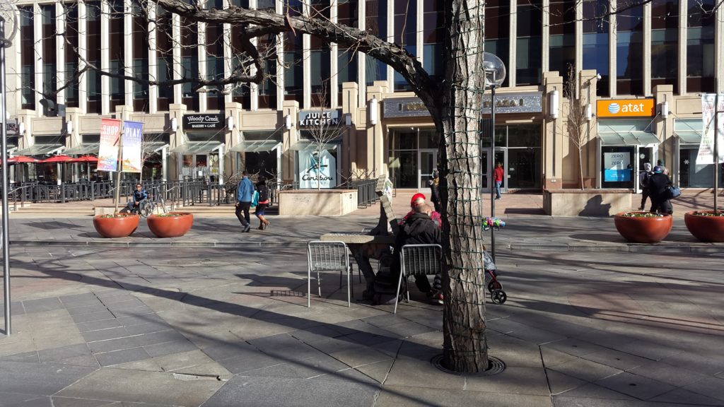 people sitting at a table in a plaza