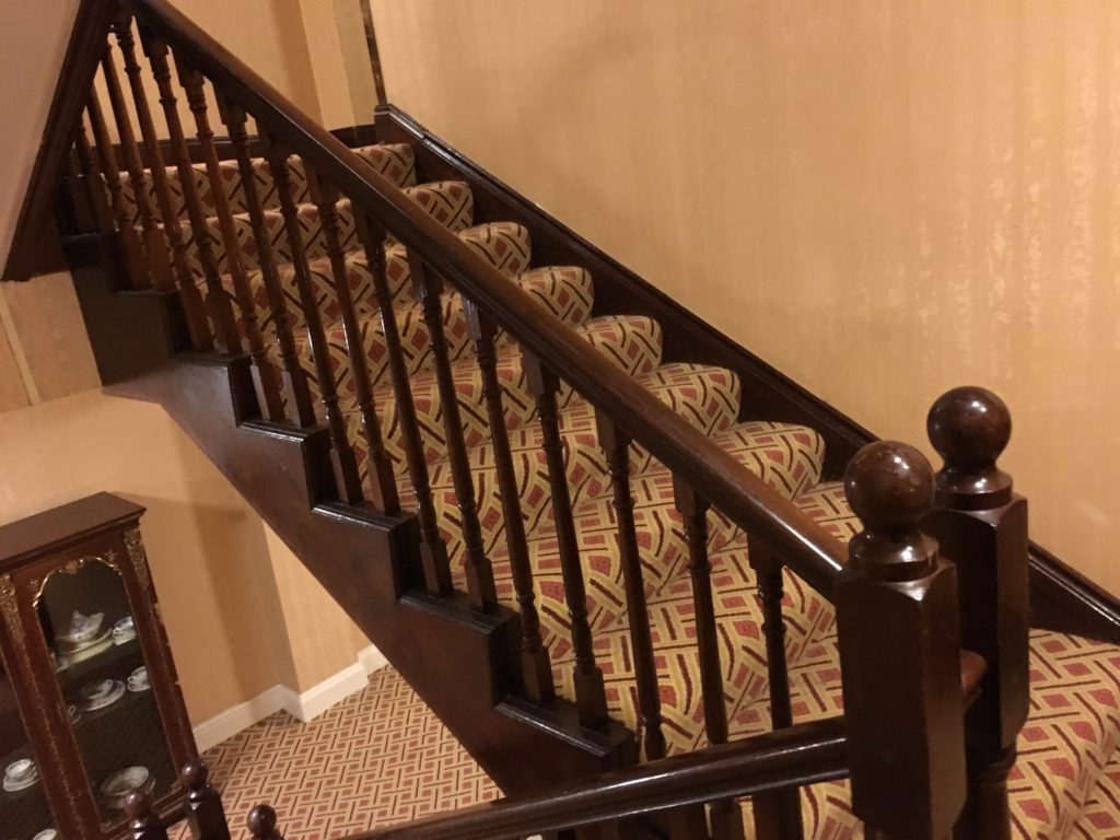 a wooden staircase with a patterned carpeted seat