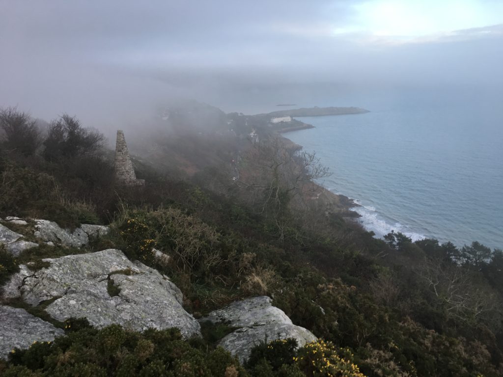 a rocky cliff with a body of water in the background