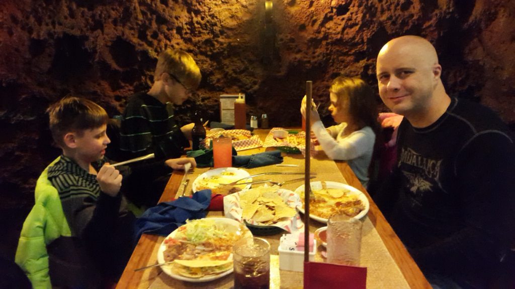 a man and kids sitting at a table with food