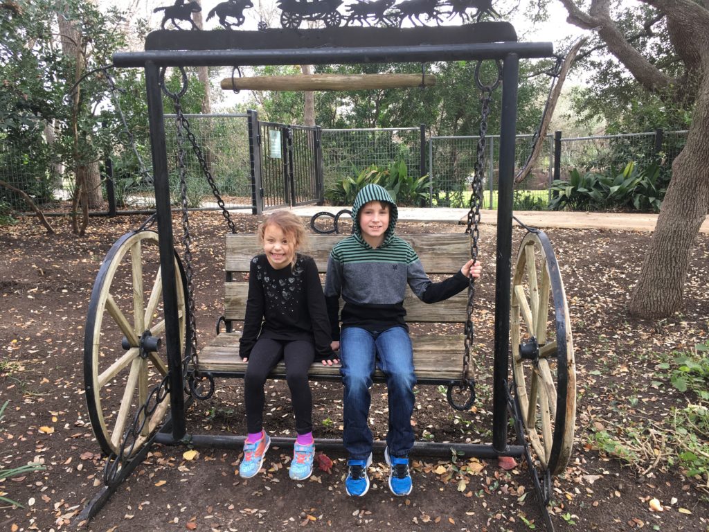 a boy and girl sitting on a swing