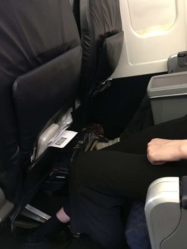 a person's legs in the seat of an airplane