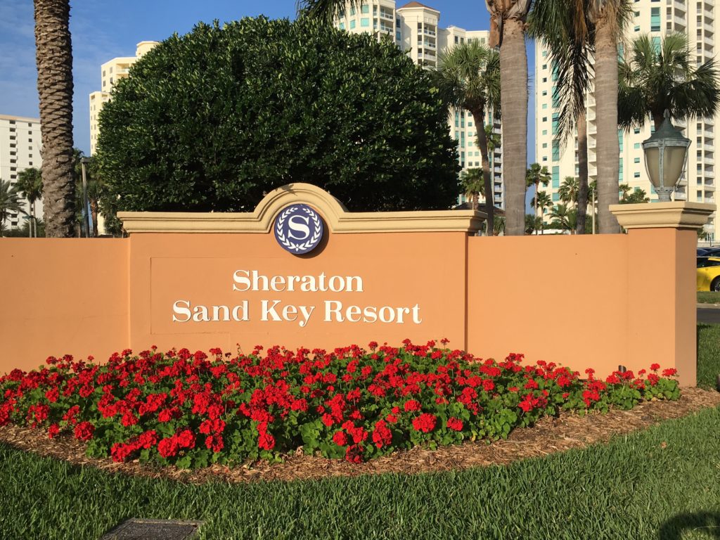 a sign with flowers and trees in front of it