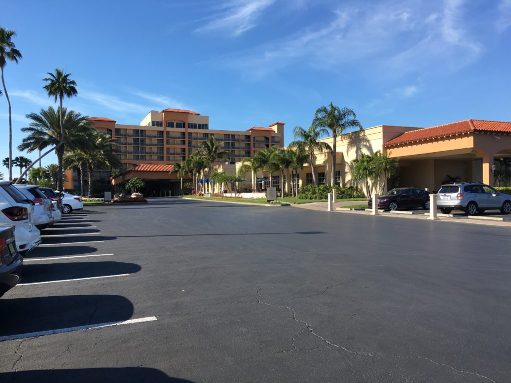 a parking lot with palm trees and a building