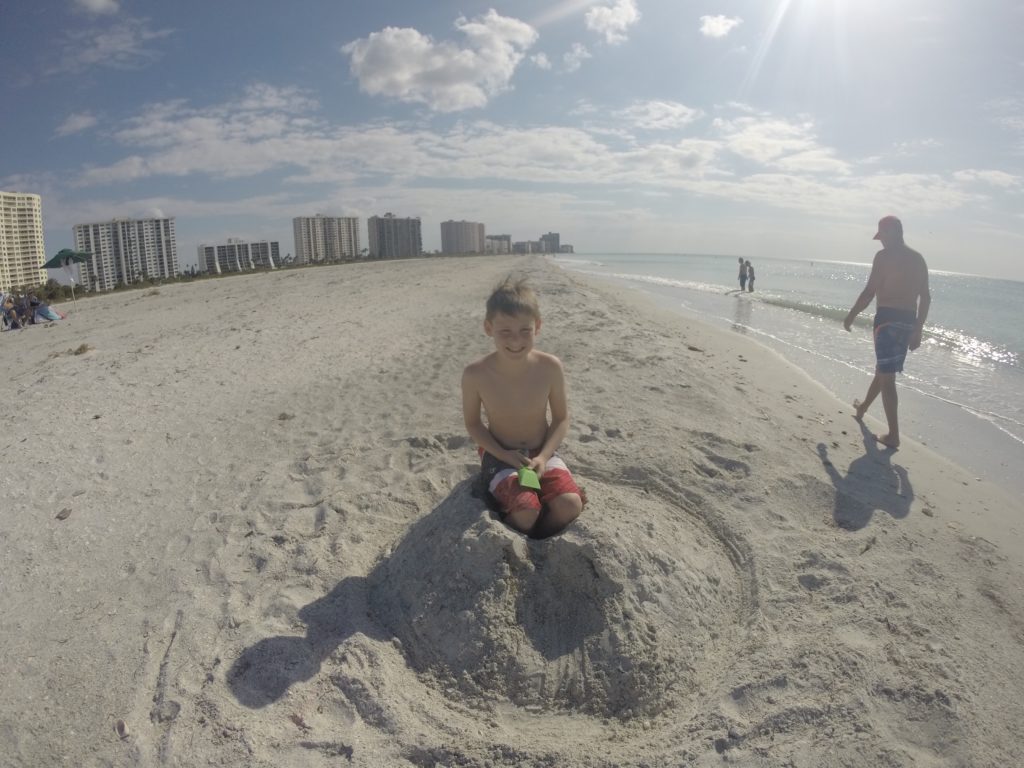 a boy sitting in sand on a beach
