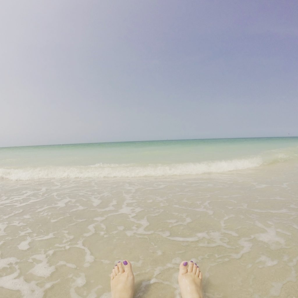 feet on a beach with water in the background