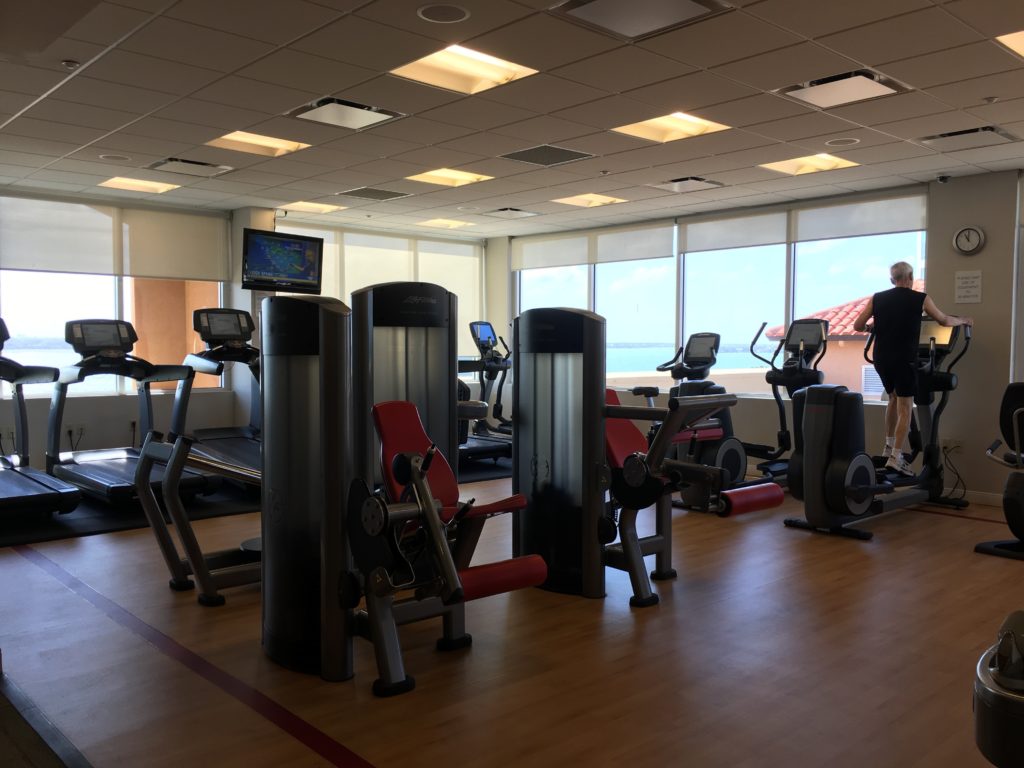 a room with exercise equipment and people standing in front of windows