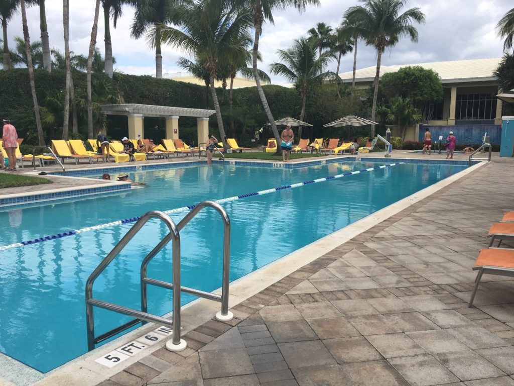 a pool with people sitting on chairs and palm trees