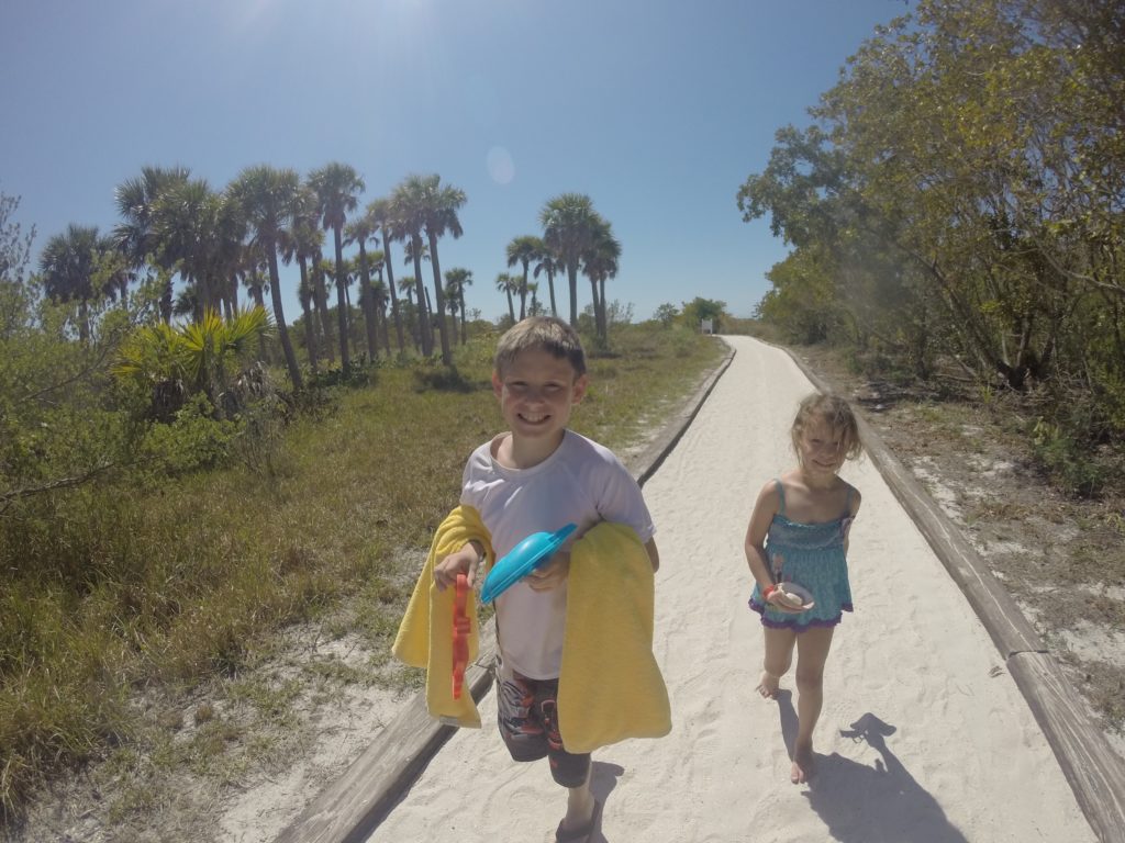 a boy and girl walking on a path with palm trees