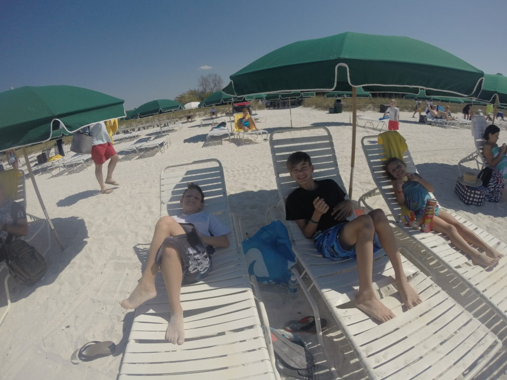 a group of people sitting on lounge chairs on a beach