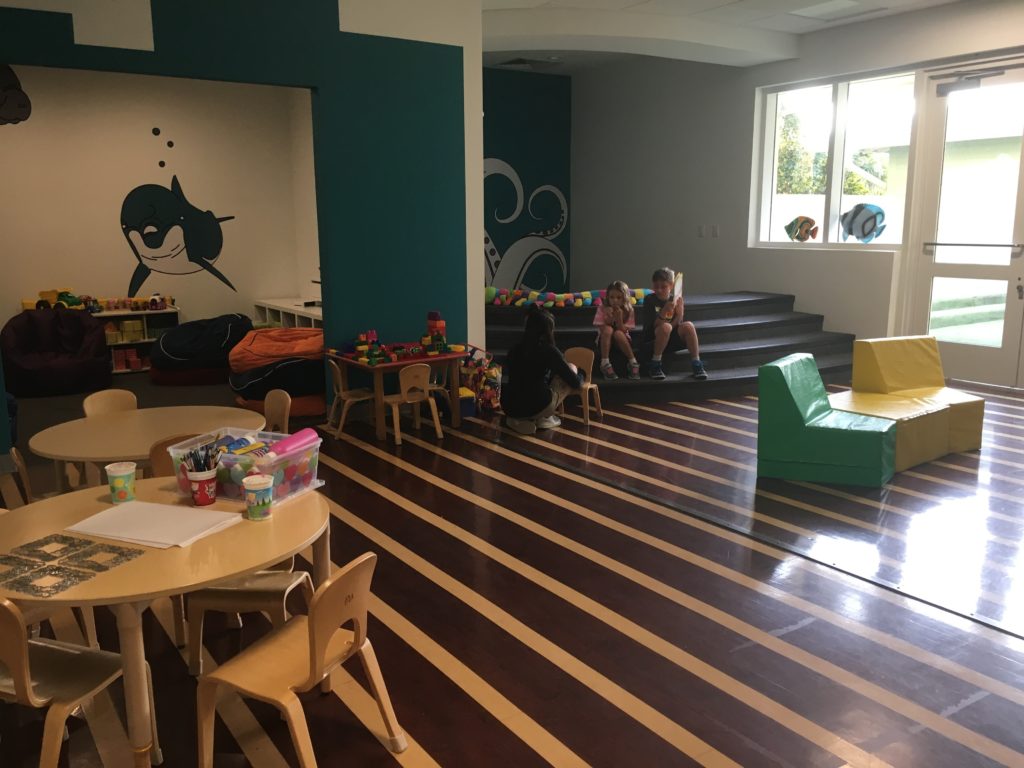 a group of kids sitting on stairs in a room with tables and chairs