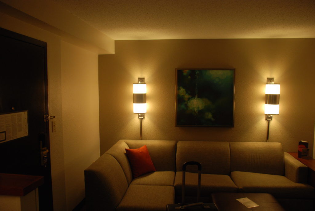 a couch with a red pillow and a suitcase on the wall