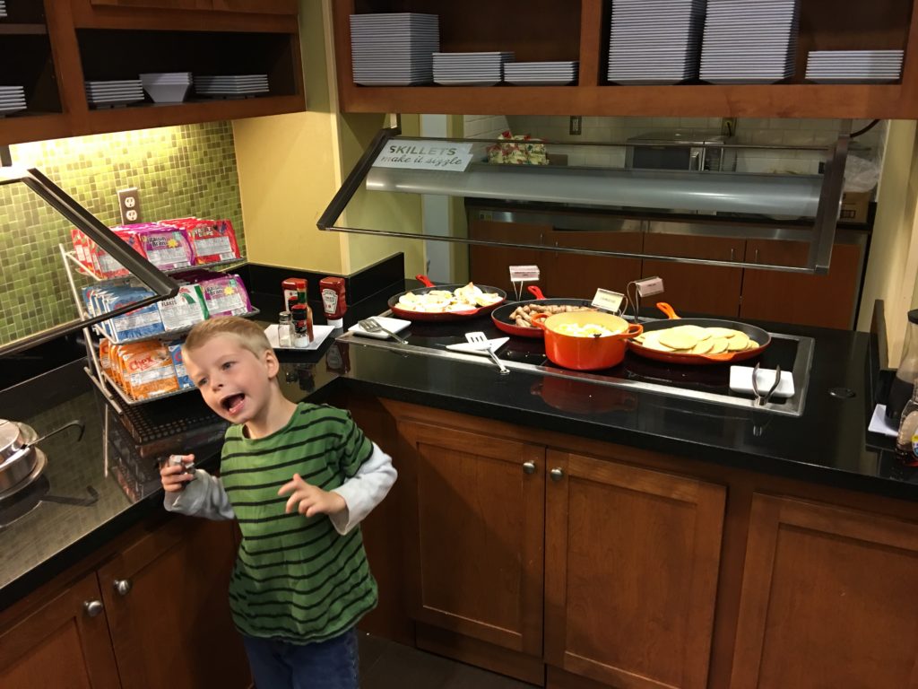 a boy standing in a kitchen with food on the counter