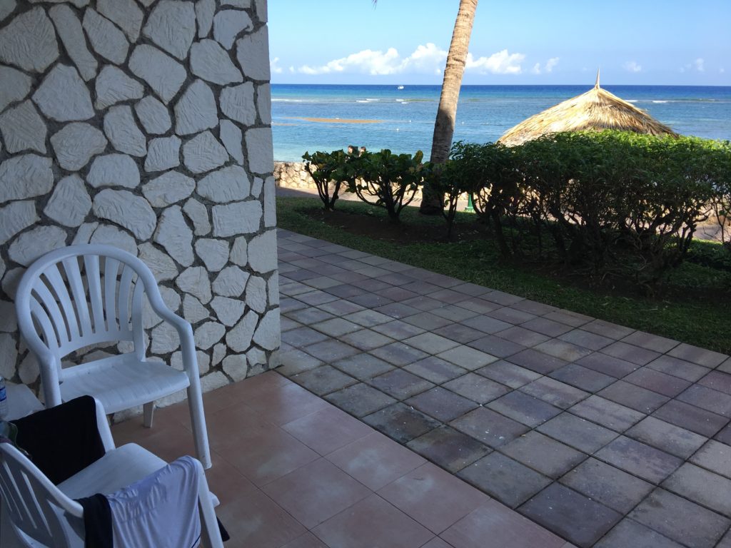 a patio with a white chair and a beach view