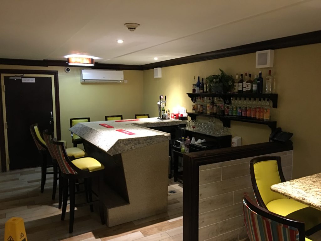 a bar with chairs and a shelf with bottles