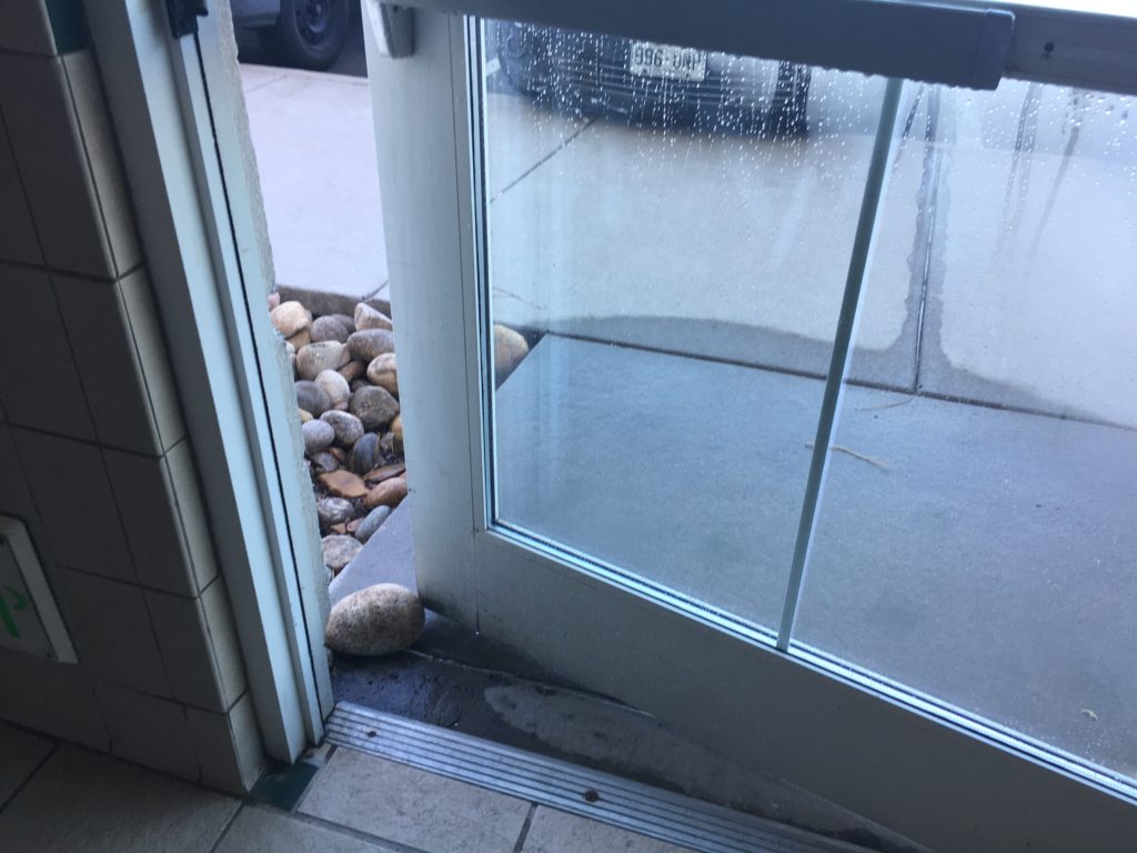 a glass door with a window and rocks on the ground