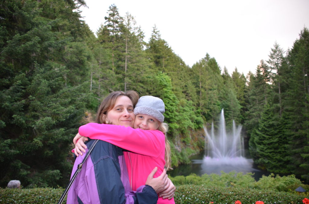 a woman and child hugging in front of a fountain