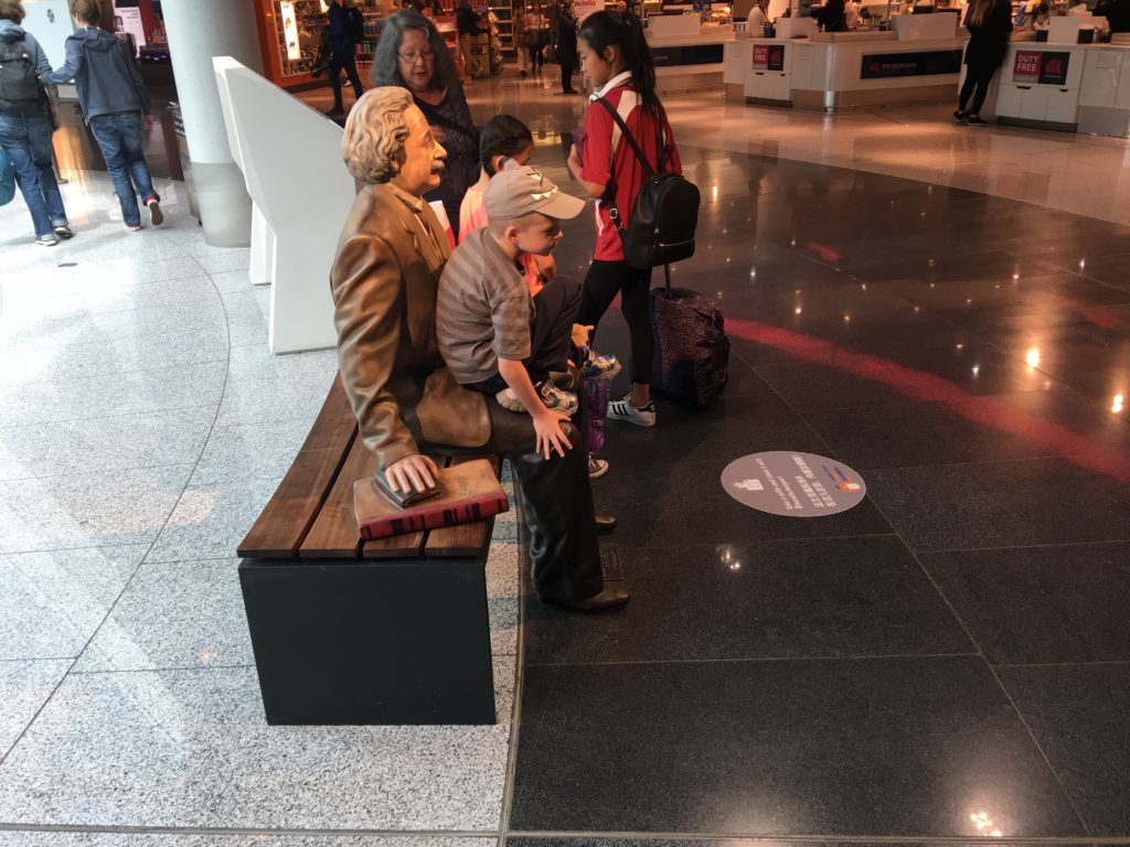a group of people standing next to a statue of a man and a woman