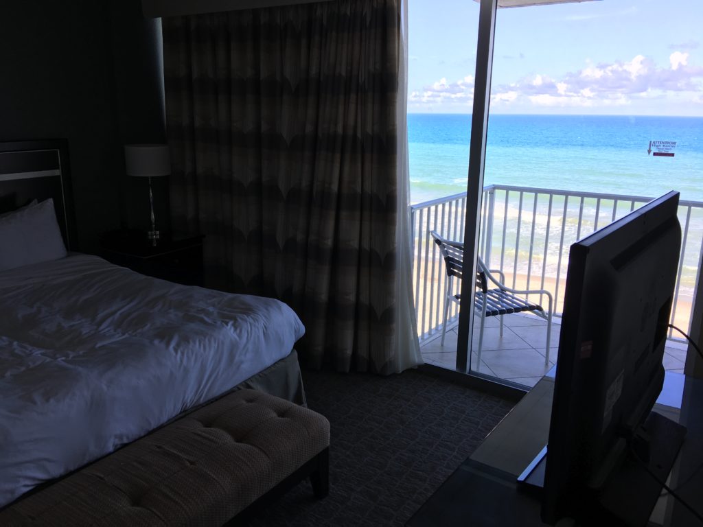 a room with a balcony and a beach view