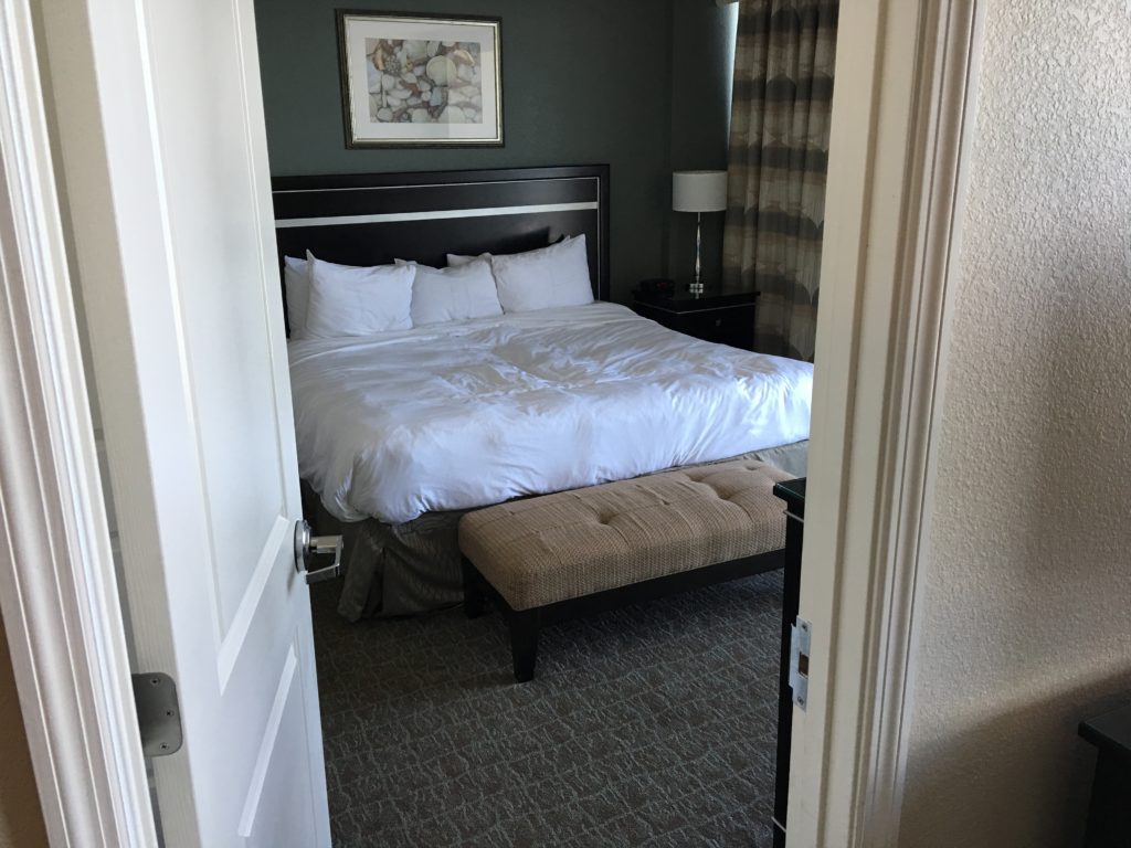 a bed with white sheets and a bench in a hotel room