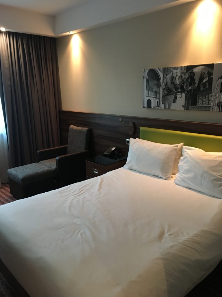 a bed with white sheets and a green headboard in a hotel room
