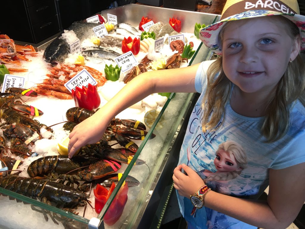 a girl standing next to a display of seafood