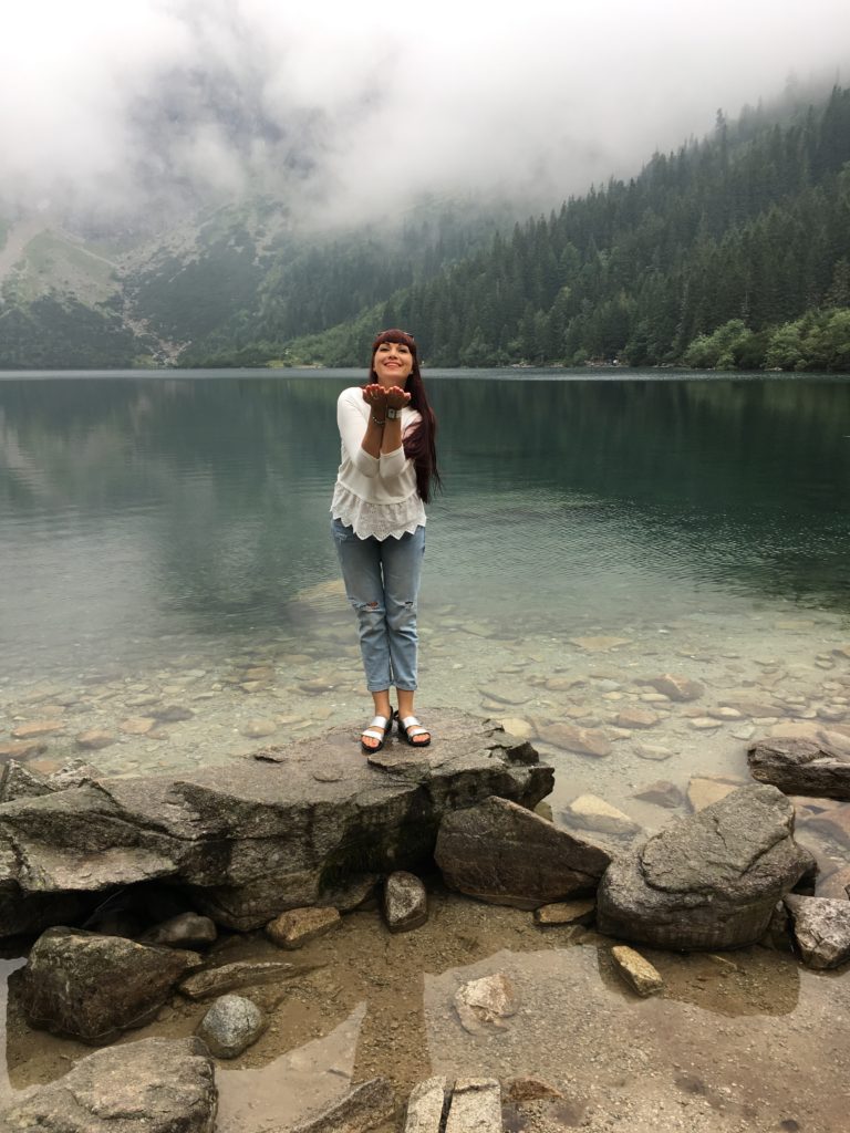 a woman standing on a rock by a lake