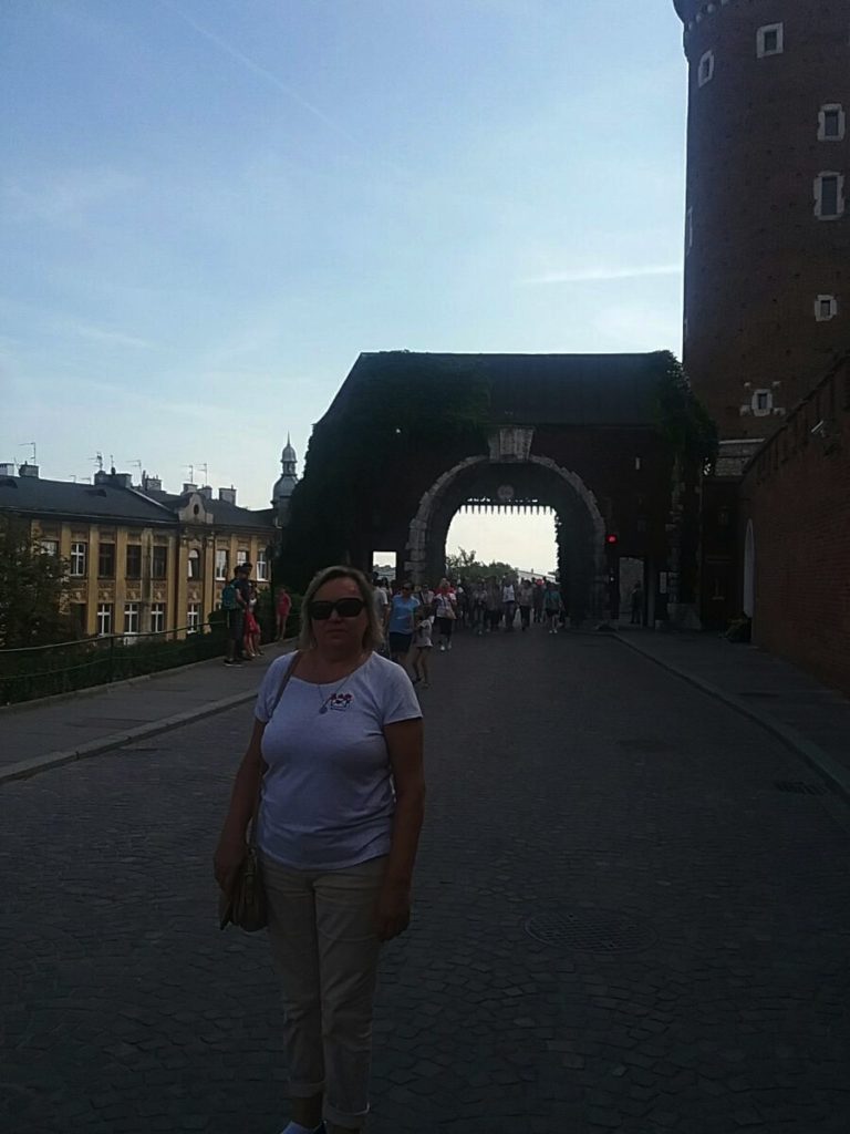 a woman standing on a street with a stone archway