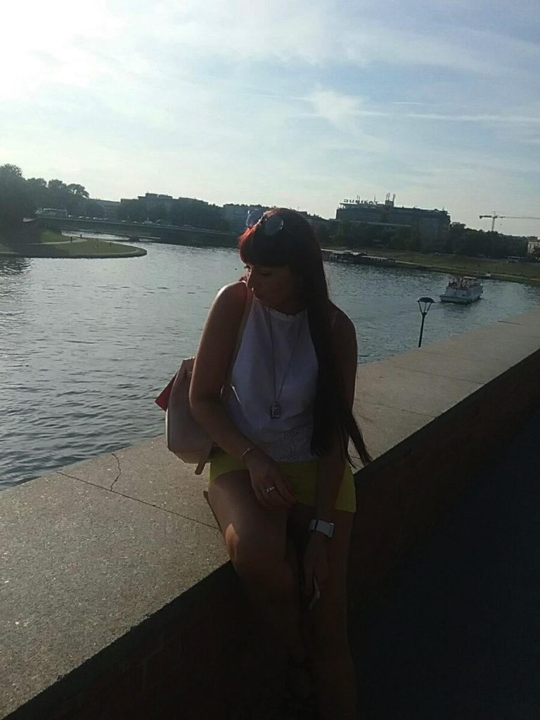 a woman sitting on a ledge by water