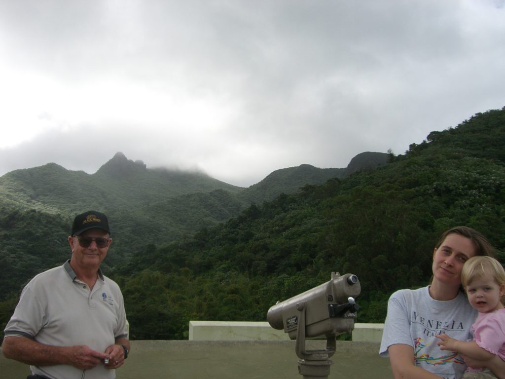 a man and woman standing next to a telescope