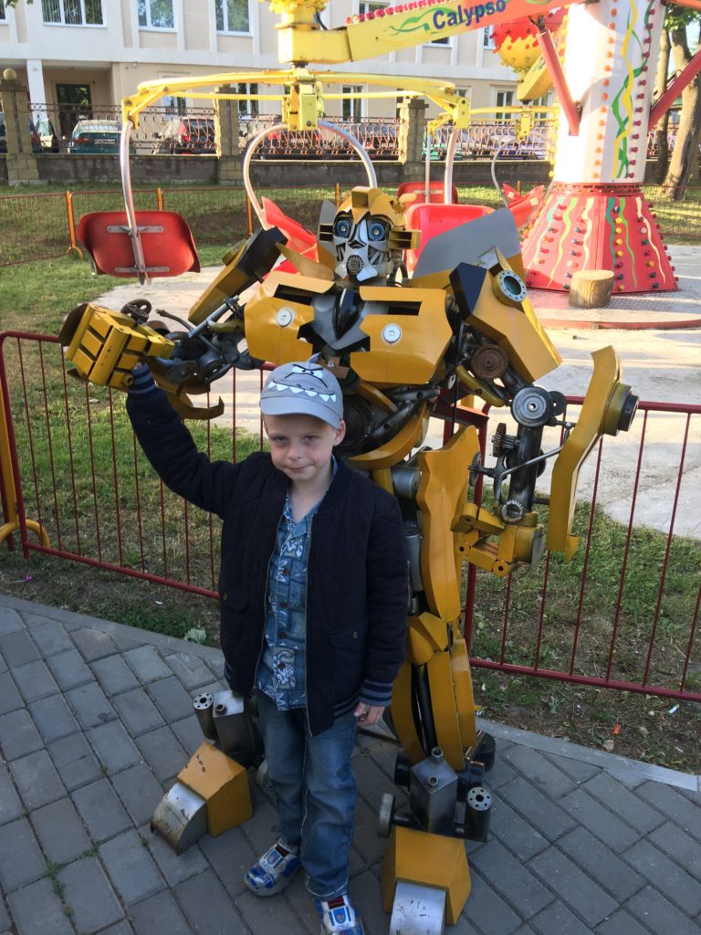 a boy standing next to a robot