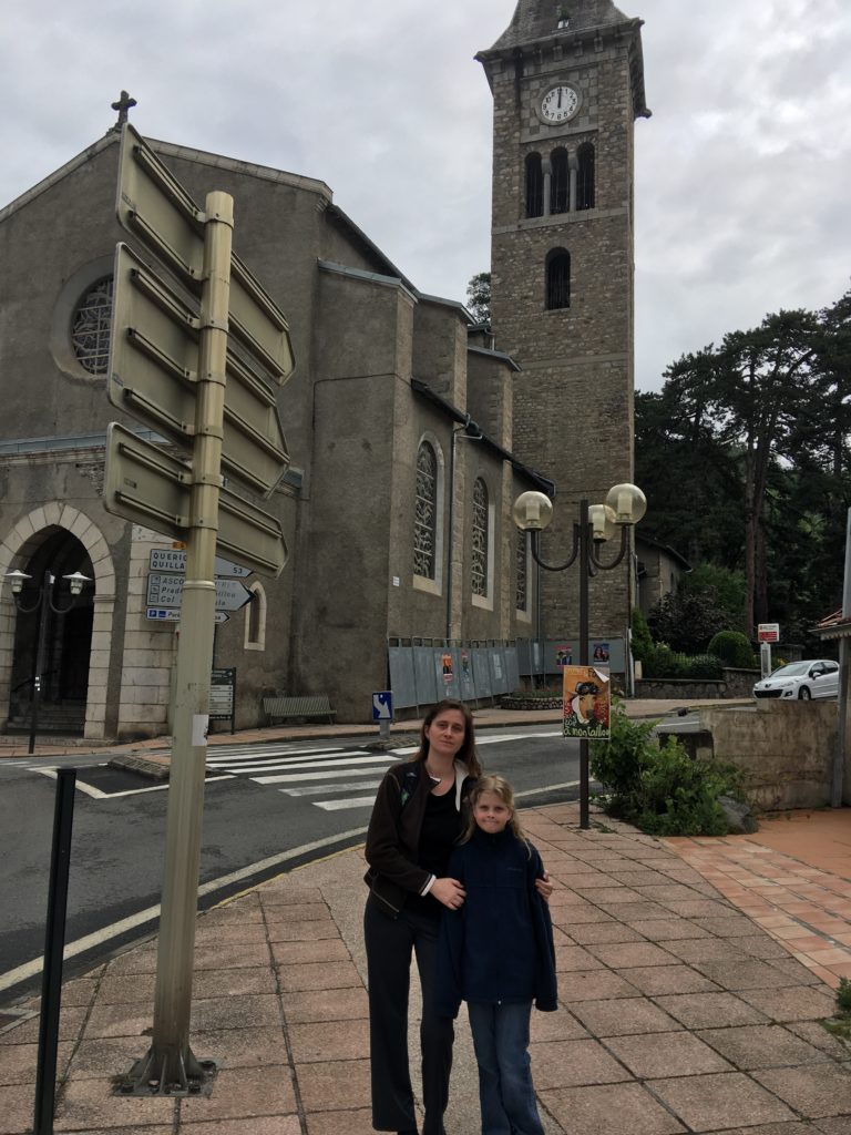 a woman and a girl standing on a sidewalk in front of a building