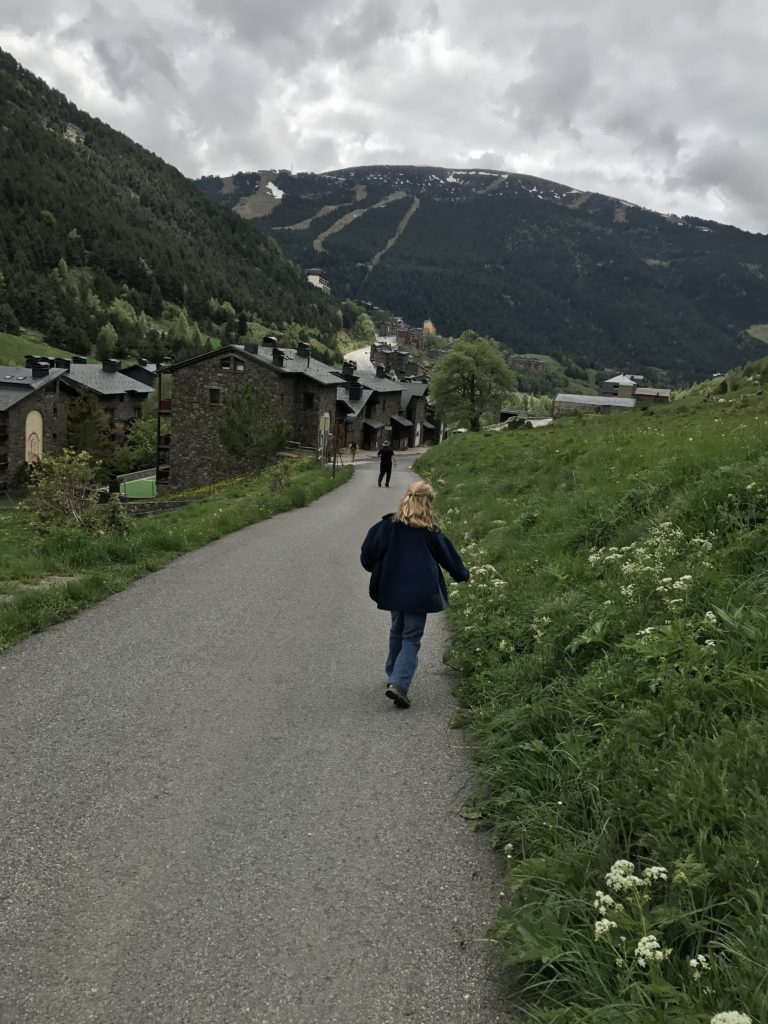a girl walking on a road with houses in the background