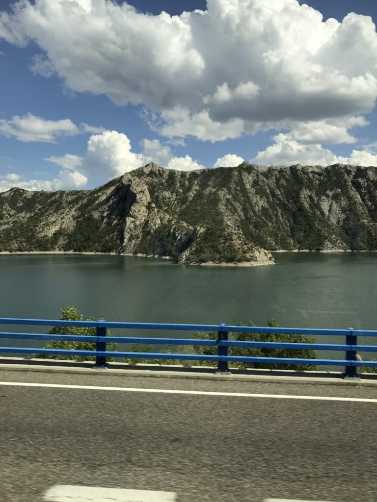 a road with a body of water and mountains