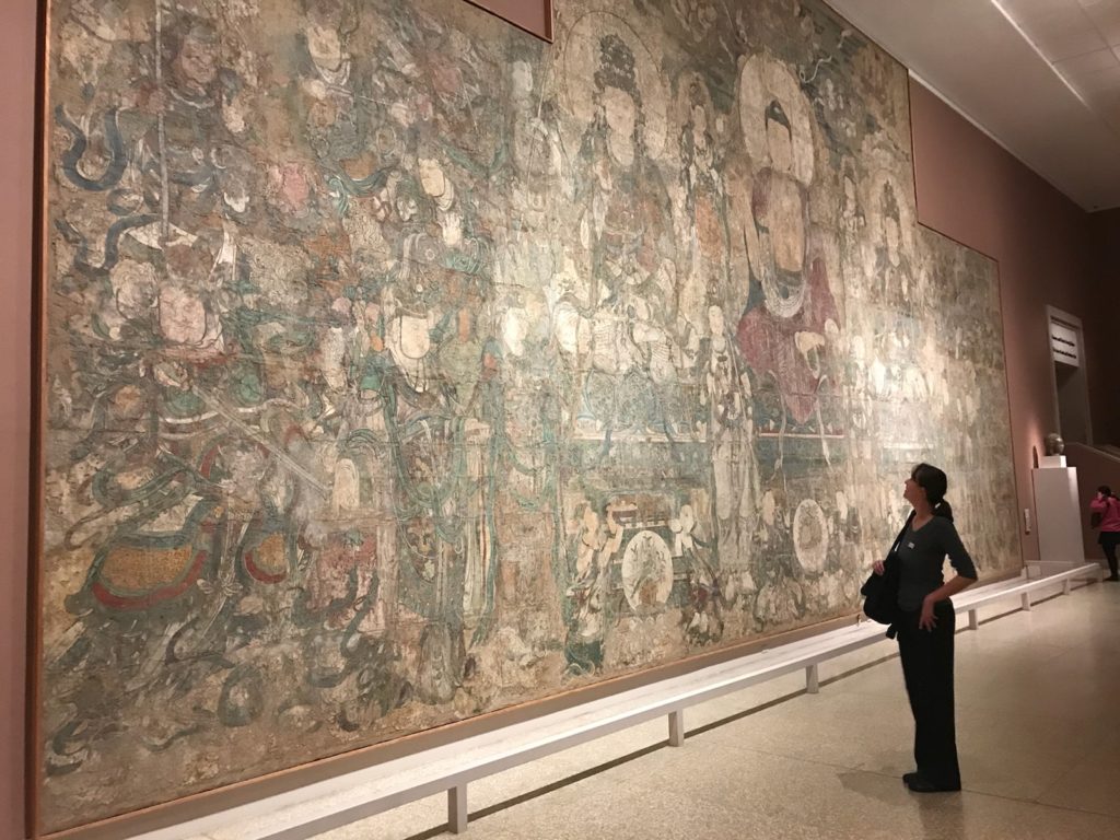 a woman looking at a large mural