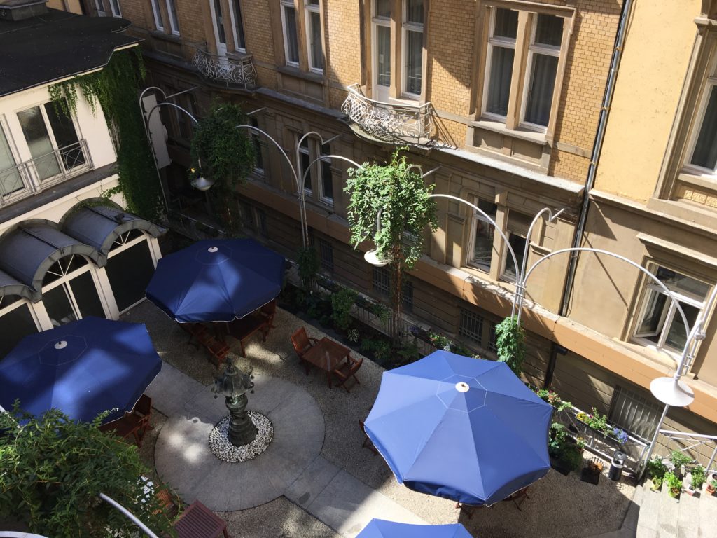 a courtyard with blue umbrellas and tables