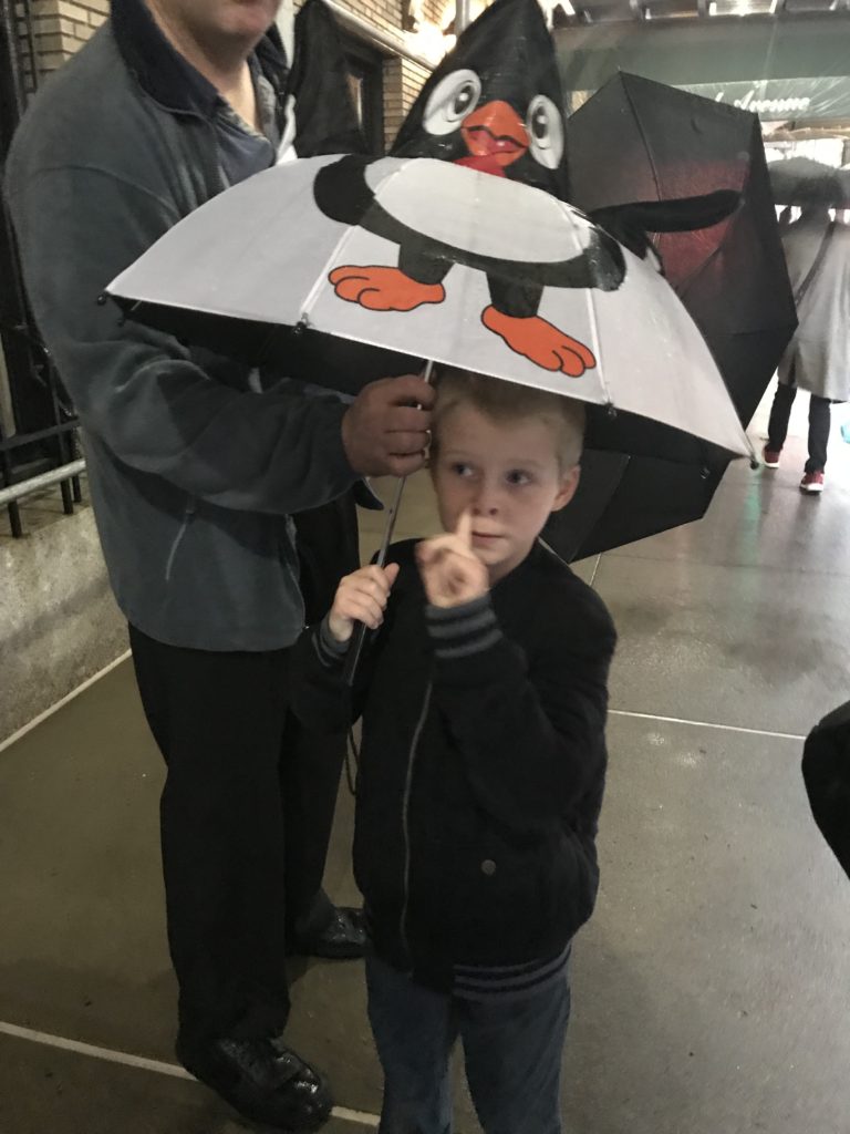 a boy holding an umbrella with a penguin on it