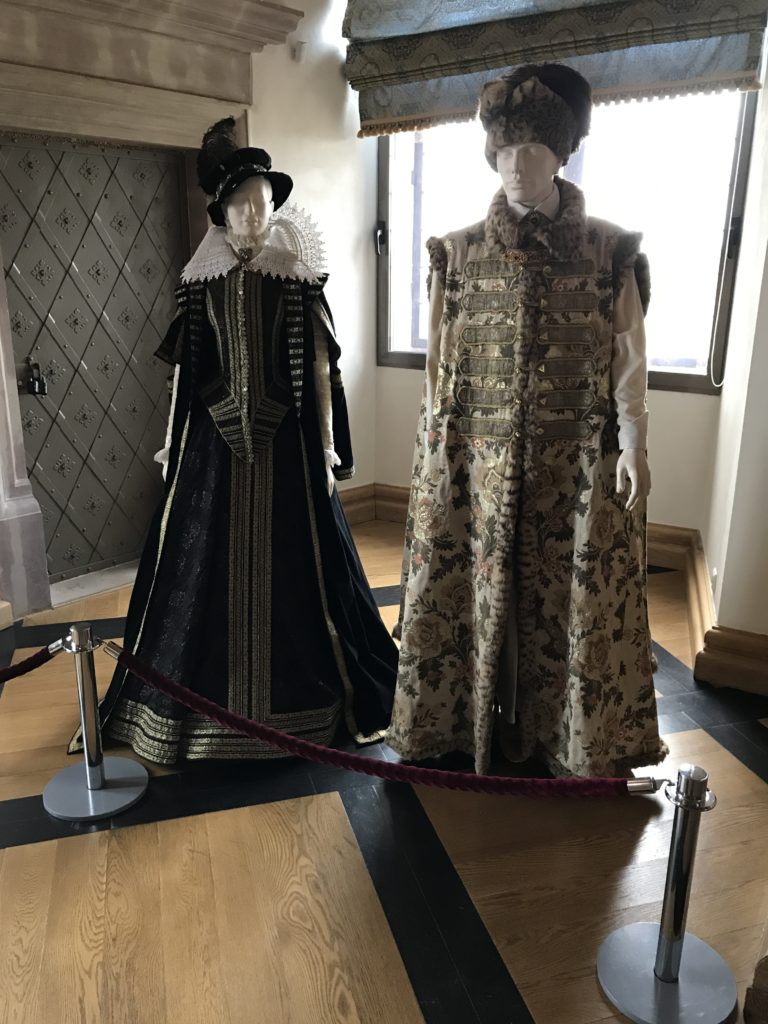 mannequins in clothing in a room with a window and a red rope
