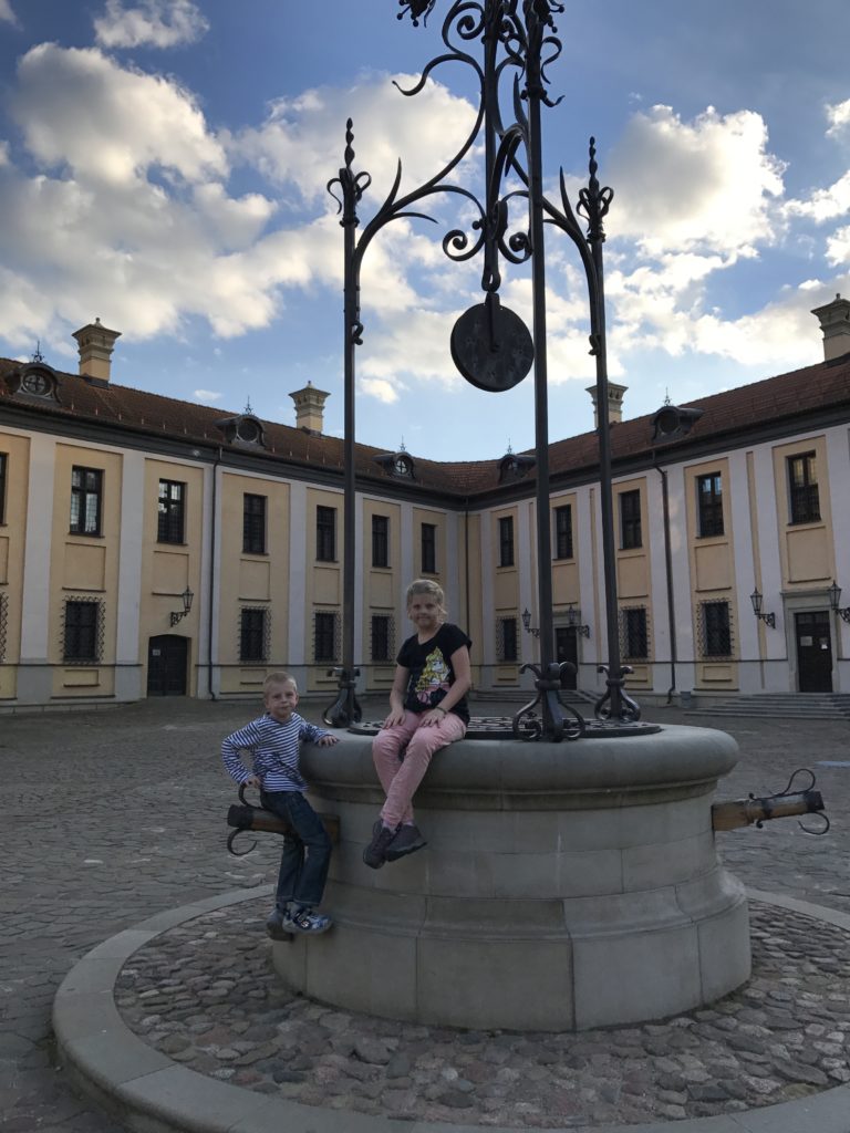 two children sitting on a stone fountain in front of a large building