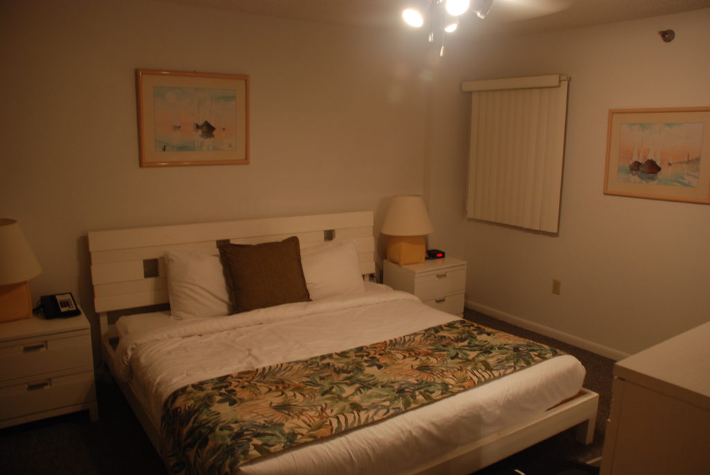 a bed with a lamp and a picture on the wall