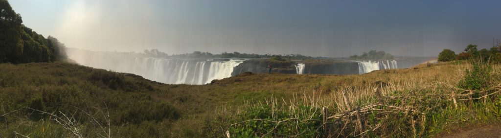 a large waterfall with a person standing in front of it