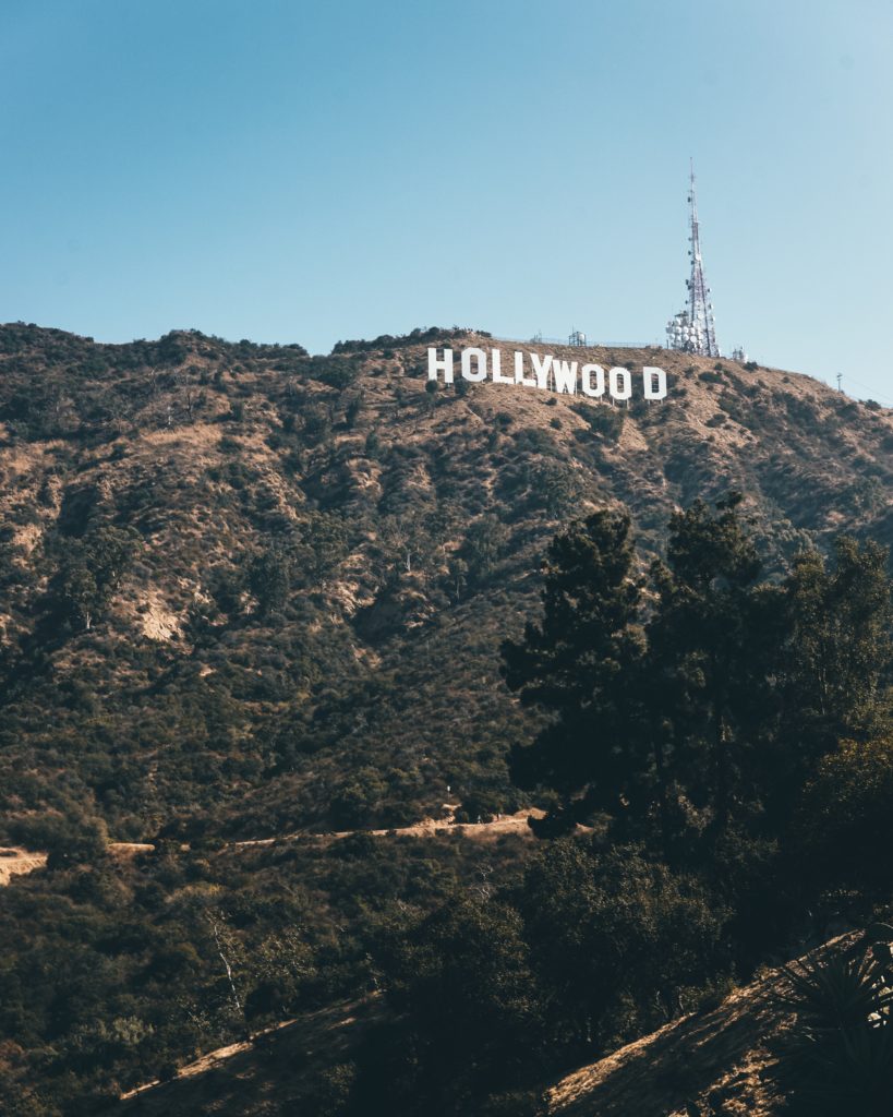 a sign on a hill with Hollywood Sign in the background